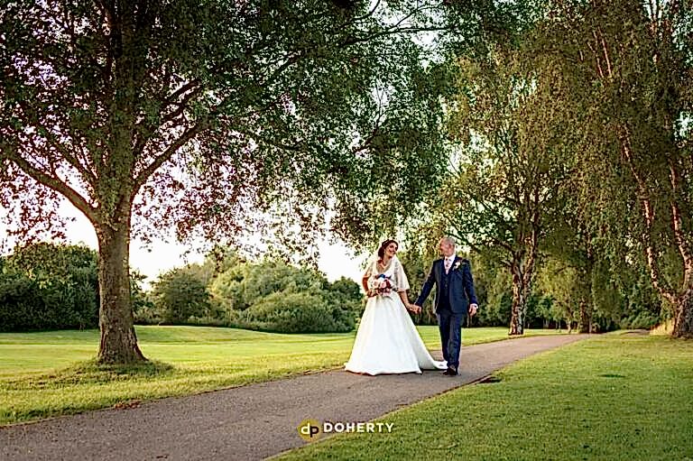 bride and groom walking at forest of arden