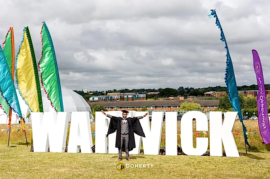 Graduation portraits with Warwick University sign in background